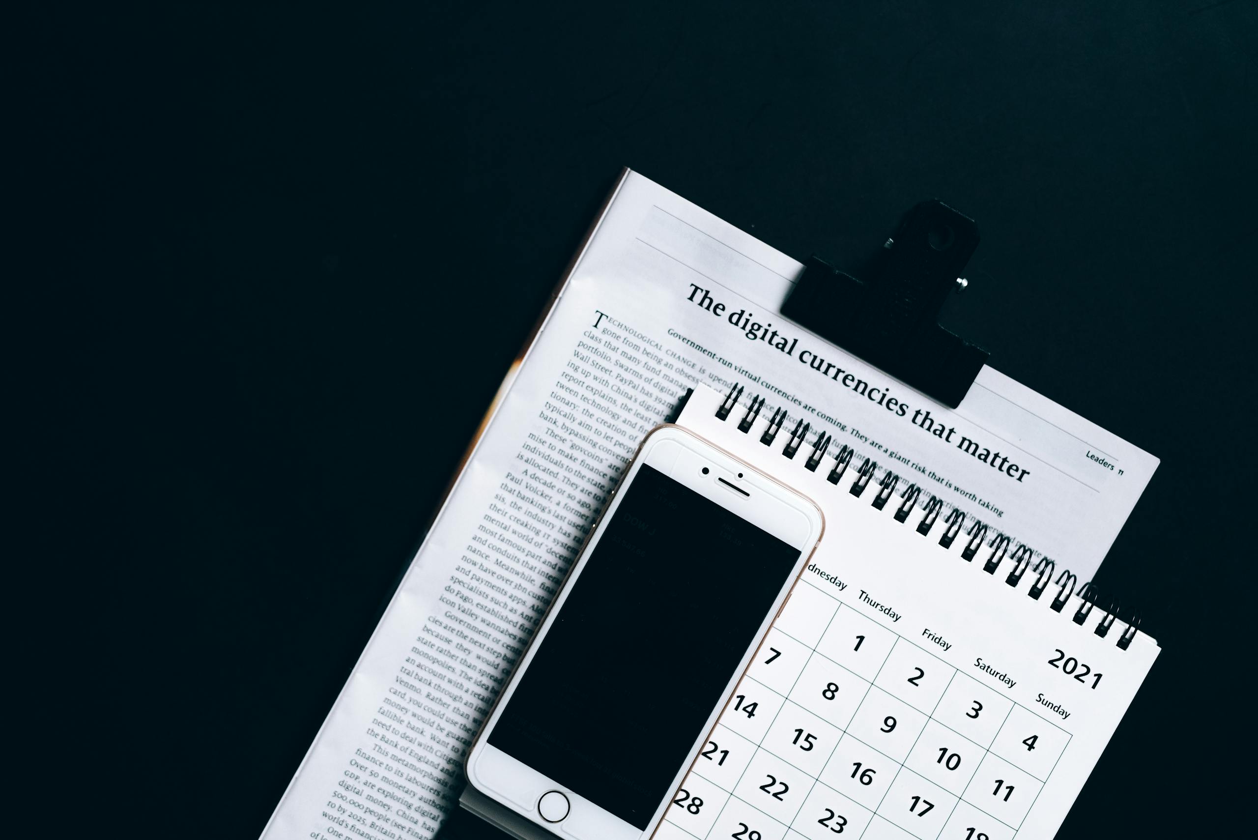 A smartphone placed on a newspaper and calendar, symbolizing modern digital finance.